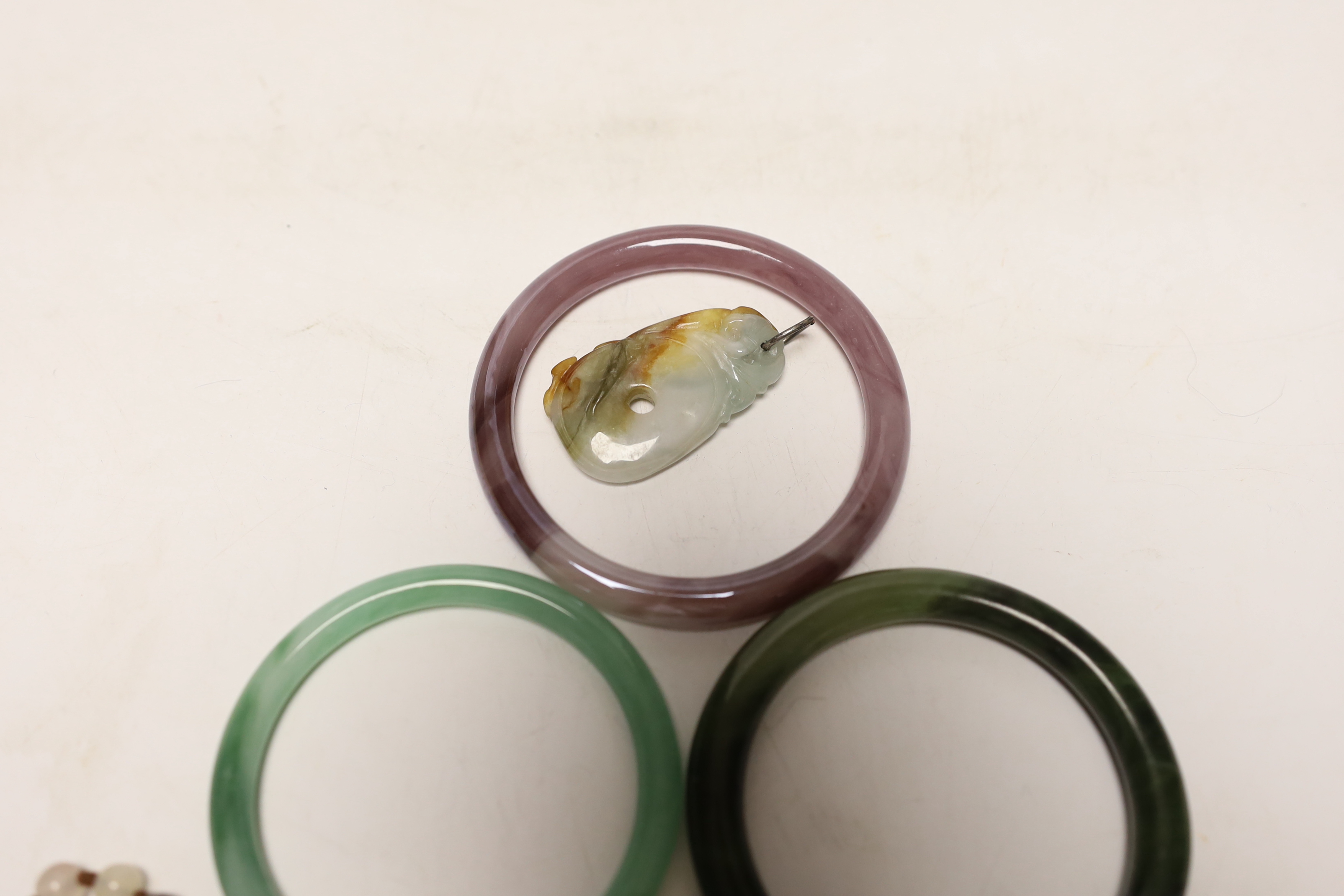 Two Chinese jade bangles, another, a jade pendant and beads